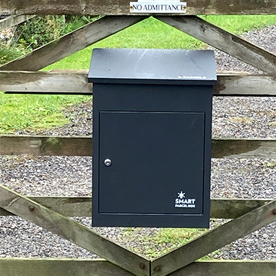 Image of the black smart parcel box mounted on a fence.