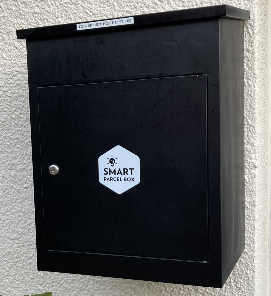 Medium black smart parcel box with an instruction sticker that reads "To deposit post lift lid".